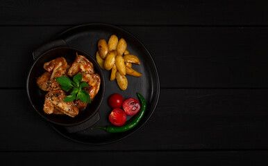 Chicken wings, fried, barbecue, with potatoes, on a black plate, top view, no people, horizontal, 