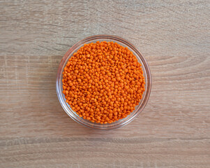 Bowl of raw grain red lentils on a wooden table