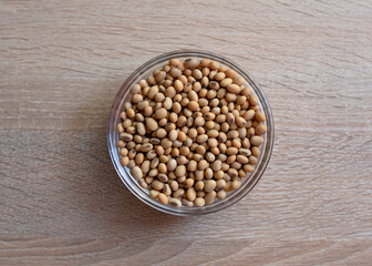 Bowl of raw grain soybeans on a wooden table
