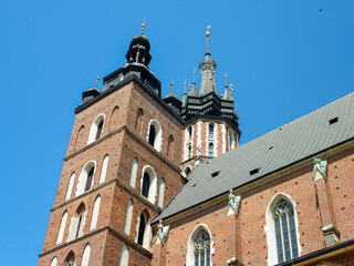 Fototapeta na wymiar A side view on St. Mary's Basilica in Cracow, Poland. The two bell towers od the basilica are towering above the city. Clear and blue sky.