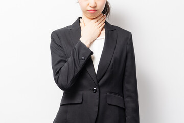 白バックの前に立っている、喉が痛いビジネスウーマン