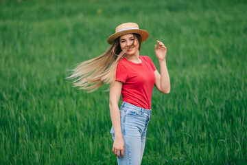 Carefree happy woman in pink t-shirt and straw hat enjoying natu