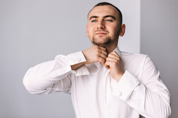 Preparing grooms for the morning, handsome groom getting dressed and getting ready for the wedding, white shirt