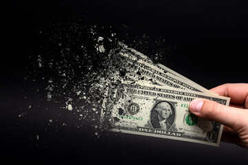 Inflation, dollar hyperinflation with black background. One dollar bill is sprayed in the hand of a man on a black background. The concept of decreasing purchasing power, inflation. - obrazy, fototapety, plakaty