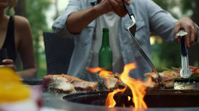 Unknown guy preparing bbq fish outside. Man chef finishing cooking process