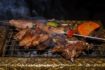 Shish Kebab with vegetables is fried on a golden grill on coals. Close-up