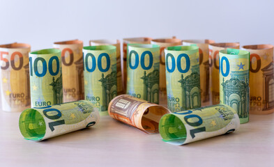 Many of the 100 and 50 euro bills, rolled up one at a time, stand in a row. Money background.