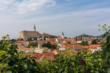Fototapeta premium View of Mikulov through the leaves with Castle in South Moravia, Czech Republic. Photo is taken from nearby hill.