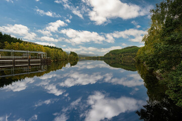 Fototapeta na wymiar River Beauly in Scotland. Perfect reflection on water surface. Clear blue sky with clouds.