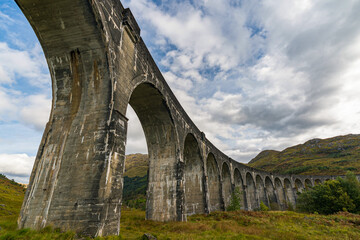 Fototapeta na wymiar The Glenfinnen viaduct is built from mass concrete, and has 21 semicircular spans of 50 feet (15 m). It is the longest concrete railway bridge in Scotland at 416 yards (380 m).