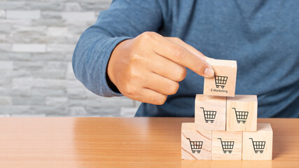 Hand arranging wood cube stacking with icon Graph and shopping cart symbol.