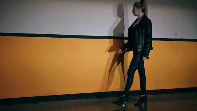 Sexy blonde girl in a leather jacket posing while walking