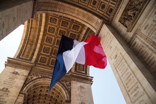 French flag waving under Arc de Triomphe in honor of VE day. Paris, France.	
