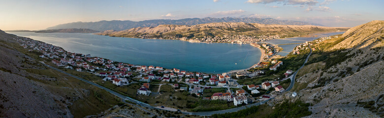 Naklejka na ściany i meble Aerial view of the town of Pag, on the island of Pag, Croatia. Seabed. Panoramic view of the city. Wild and desert nature. Headlands and cliffs of the Croatian coast. Houses on the sea at sunset