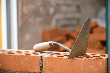 Construction trowel on a brick wall. Construction site concept.