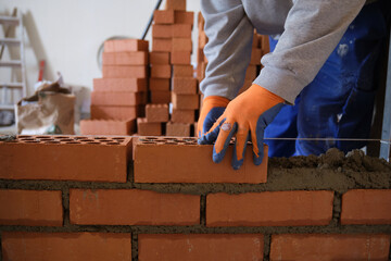 Construction worker building a brick wall. Man bricklaying. Mason laying bricks.