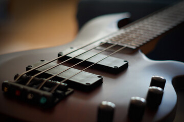 Obraz na płótnie Canvas Closeup shot of a smooth body, pickups, bridge, knobs and strings of a bass guitar musical instrument with backlight