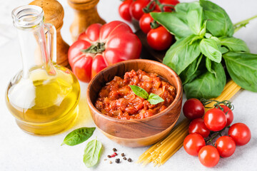 Tomato sauce Marinara, olive oil, uncooked pasta, green basil leaf and tomatoes. Italian cuisine food ingredients assortment