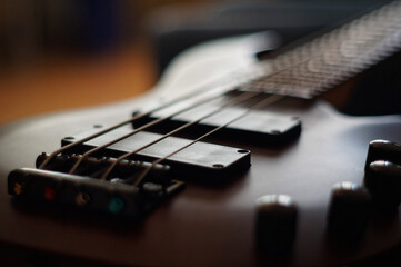 Fototapeta premium Closeup shot of a smooth body, pickups, bridge, knobs and strings of a bass guitar musical instrument with backlight