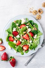 Healthy salad with strawberries, walnuts and cheese, top view