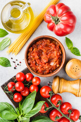 Italian cuisine food ingredients. Marinara sauce, tomatoes, olive oil, green basil and uncooked dry spaghetti pasta