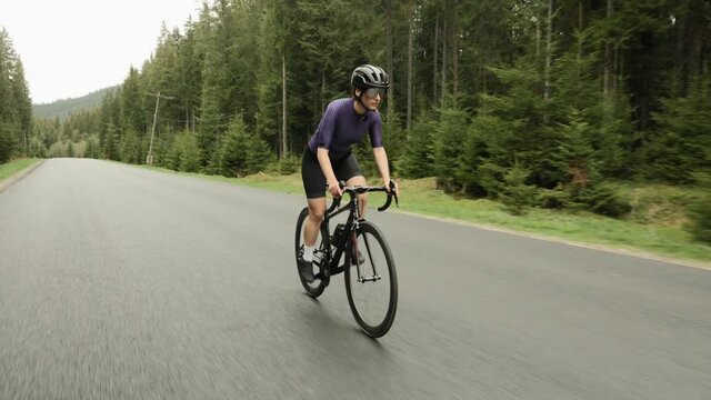 Woman cycling. Cyclist riding bicycle. Athlete rides road bike on mountain road