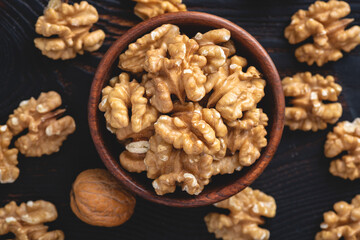 Obraz premium Walnuts in a bowl on black stone background, top view, selective focus