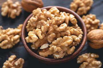 Peeled walnuts in bowl on black stone background, closeup view. Healthy nuts for snack. Toned image - 433969158