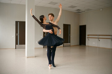 Female and male ballet dancers dancing at barre