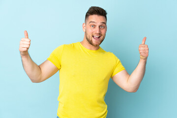 Russian handsome man isolated on blue background giving a thumbs up gesture