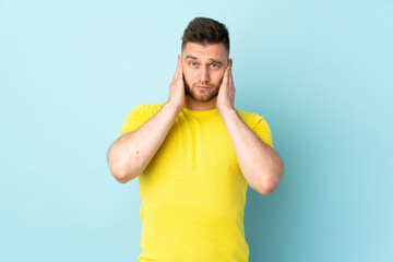 Russian handsome man isolated on blue background frustrated and covering ears