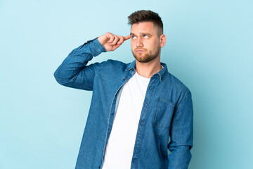 Russian handsome man isolated on blue background making the gesture of madness putting finger on the head