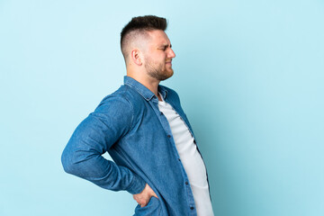 Russian handsome man isolated on blue background suffering from backache for having made an effort