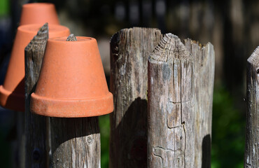 On a wooden garden fence hang a couple of empty clay flower pots