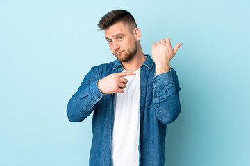 Russian handsome man isolated on blue background making the gesture of being late