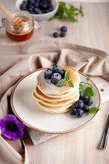 Homemade pancakes with blueberries and powdered sugar on the white table vertical photo