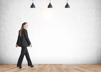 Fototapeta premium Businesswoman walking on grey background on parquet floor, mockup empty wall