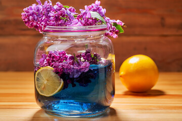 homemade lemonade with lilac flowers and lemon in jar