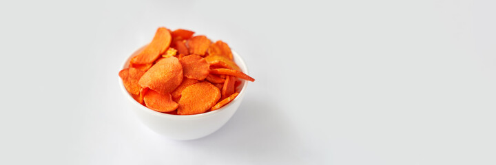 Crispy dried food. Organic tasty chips. Homemade snacks. Sliced carrot. Healthy vegetables. Orange pile Trend natural dish. Horizontal banner. Copyspace