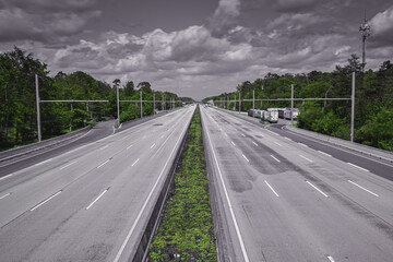 Motorway in Germany with 8 lanes completely empty dramatic in black an white with green plants