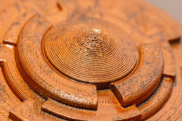 Close-up of brass color plastic part printed on a 3D printer. Cover part of plastic cryptex.