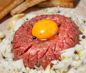 Close up of tasty raw beef steak tartare with garlic, egg yolk and onions - typical variant of Czech cuisine.