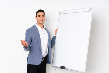 Young caucasian handsome man isolated on purple background giving a presentation on white board