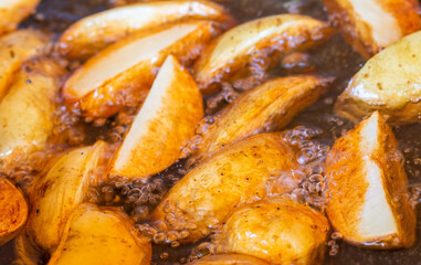 Close-up of chopped pieces of potatoes fried in oil. Preparation of tasty American potatoes for bbq.