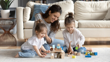 Happy caring young Caucasian mother have fun play with small daughter at home in living room....