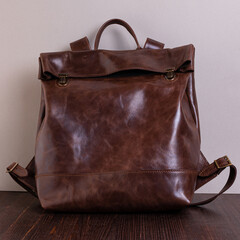 Brown handmade backpack made of genuine leather with a marble pattern. The backpack is on a brown wooden table with a gray background