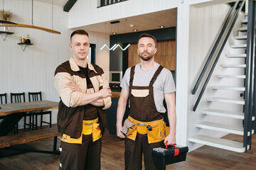 Obraz premium Two plumbers in uniform standing in front of camera in living-room of large house