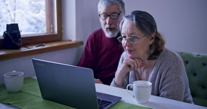 elderly couple understands how the computer works, husband and wife put on glasses to understand laptop