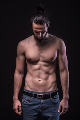 Fototapeta na wymiar Studio portrait of a beautiful masculine bearded shirtless man. Low Key photo of male athletic body.