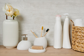 A group of white containers with bodycare stuff, basket with clean towels and vase with flowers